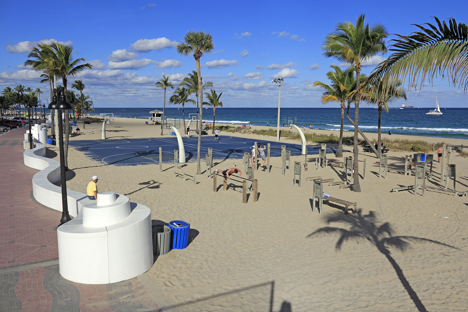 Fort Lauderdale, Florida, USA - January 23, 2014: Variety of people, mostly men, exercising in the public exercise equipment area and basketball courts of Fort lauderdale Beach Park on a mostly sunny day.
